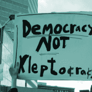 Protest placard reading "democracy not kleptocracy".